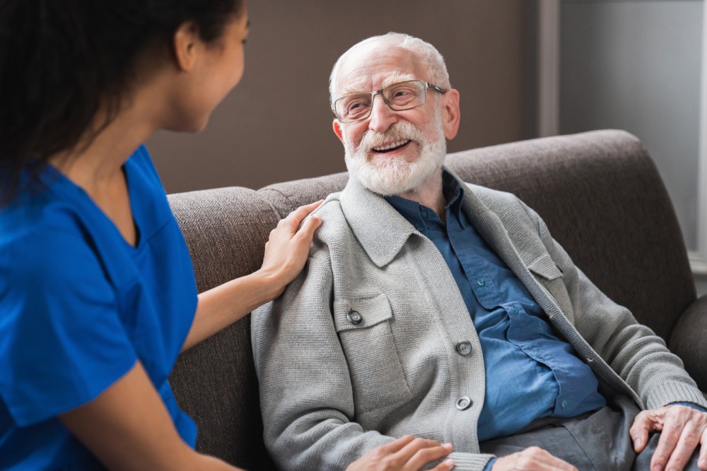 Female Caregiver Talking To Happy Senior Man